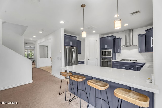 kitchen featuring wall chimney range hood, a peninsula, stainless steel appliances, and visible vents