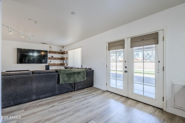 unfurnished living room with french doors, track lighting, and light hardwood / wood-style floors