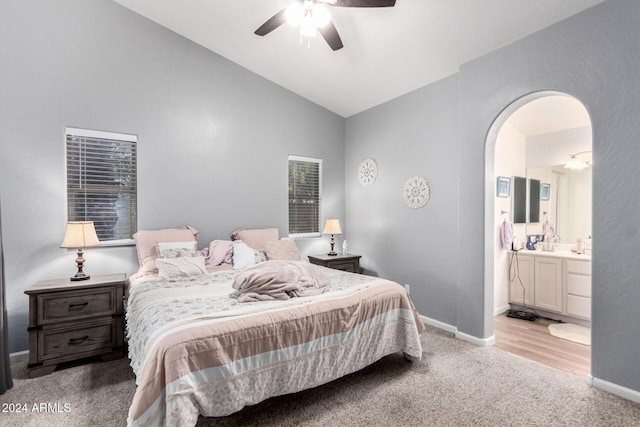 carpeted bedroom with ceiling fan, lofted ceiling, and ensuite bath