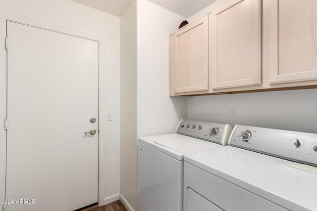 clothes washing area featuring separate washer and dryer, hardwood / wood-style floors, and cabinets