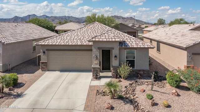 22574 W Moonlight Path, Buckeye, AZ 85326 - view of front of property with a garage, a mountain view, concrete driveway, stucco siding, and stone siding