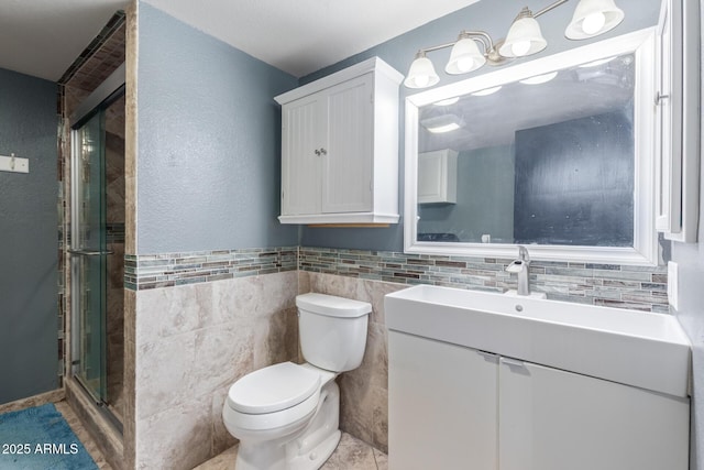 bathroom featuring vanity, a shower stall, toilet, and tile walls