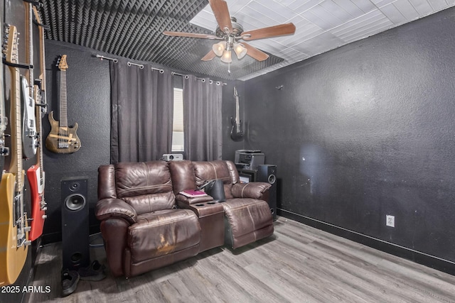 cinema room with a textured wall, wood finished floors, and a ceiling fan