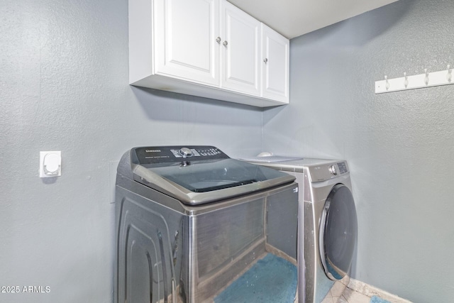 washroom featuring cabinet space, separate washer and dryer, and a textured wall