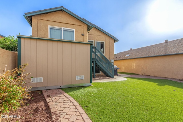 rear view of house with a lawn, a patio, and stairs