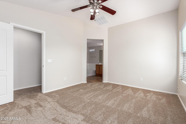 unfurnished bedroom featuring light carpet, multiple windows, ensuite bath, and ceiling fan