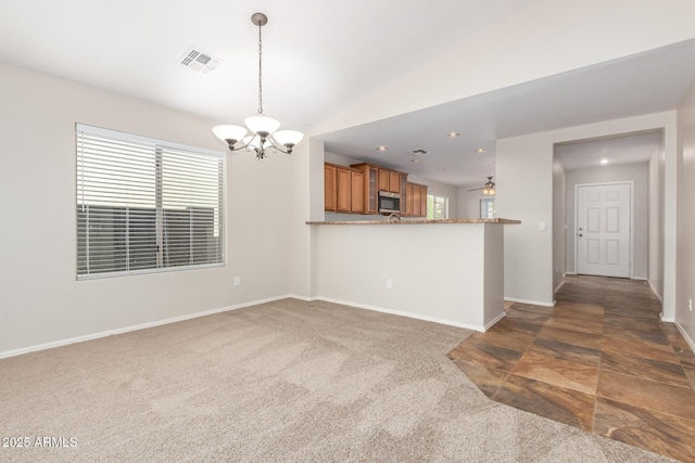 kitchen with dark colored carpet, kitchen peninsula, lofted ceiling, decorative light fixtures, and ceiling fan with notable chandelier