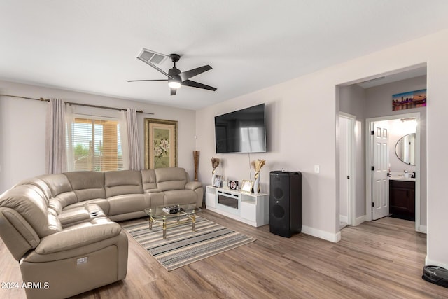 living room featuring light wood-type flooring, ceiling fan, and sink