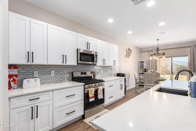 kitchen with white cabinetry, sink, stainless steel appliances, and decorative light fixtures