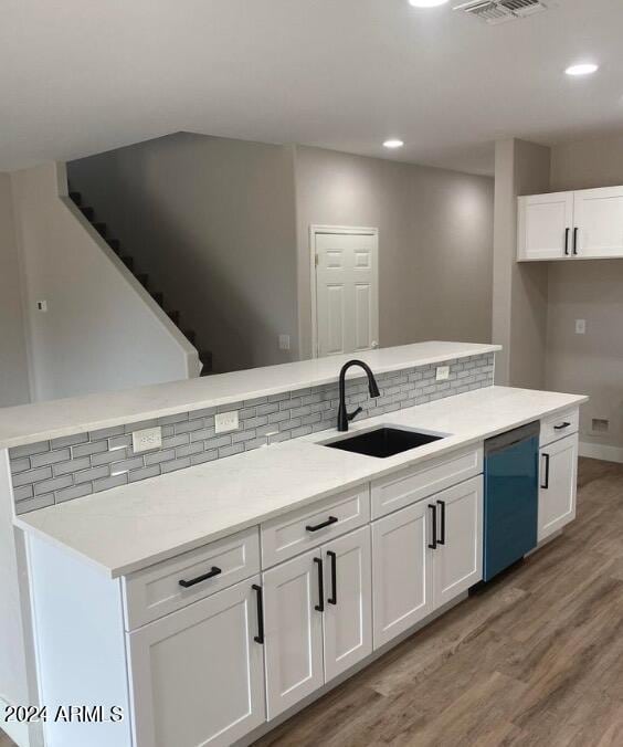 kitchen featuring white cabinetry, sink, black dishwasher, decorative backsplash, and light wood-type flooring