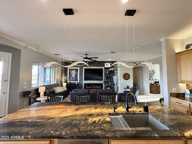 kitchen featuring hanging light fixtures, crown molding, sink, and a fireplace