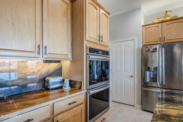 kitchen with light brown cabinets, light tile patterned floors, ornamental molding, appliances with stainless steel finishes, and dark stone counters