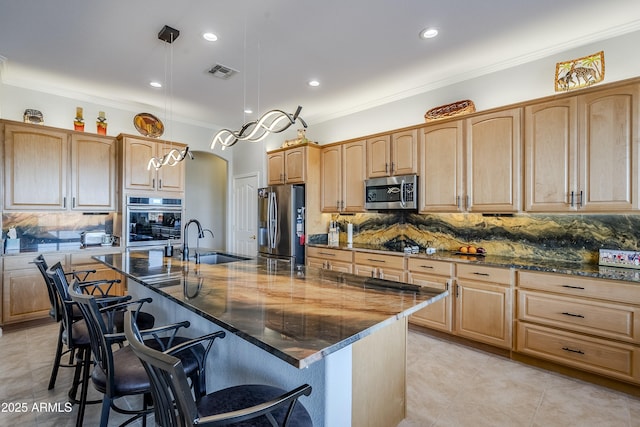 kitchen featuring a breakfast bar, sink, appliances with stainless steel finishes, dark stone counters, and a large island