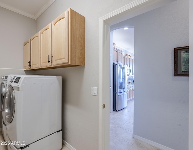 laundry area featuring light tile patterned flooring, cabinets, ornamental molding, and washer and clothes dryer