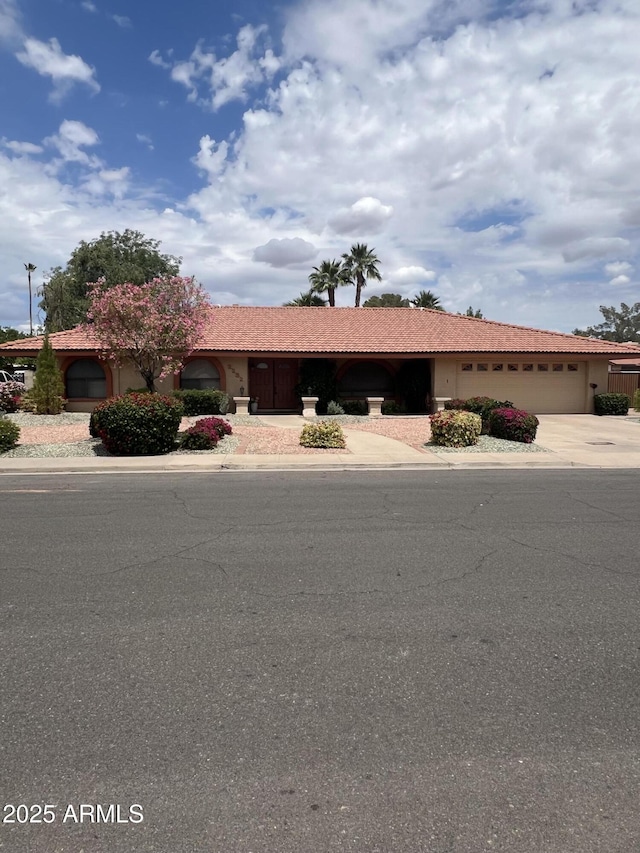 view of front of property with a garage, a tile roof, concrete driveway, and stucco siding