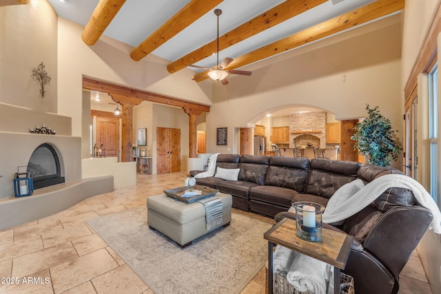 living room featuring ceiling fan, a towering ceiling, and beamed ceiling