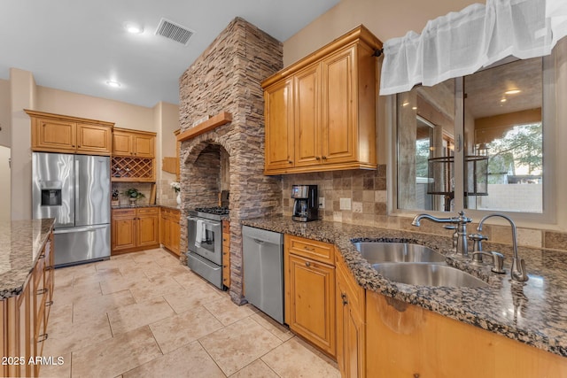 kitchen featuring backsplash, dark stone counters, sink, and stainless steel appliances