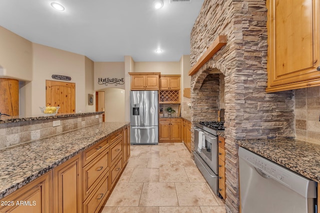 kitchen featuring appliances with stainless steel finishes, dark stone countertops, and backsplash