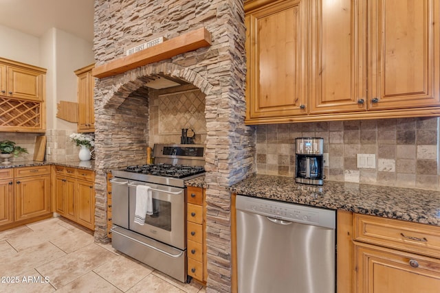 kitchen with tasteful backsplash, appliances with stainless steel finishes, and dark stone countertops