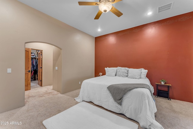 carpeted bedroom with a spacious closet, ceiling fan, and a closet