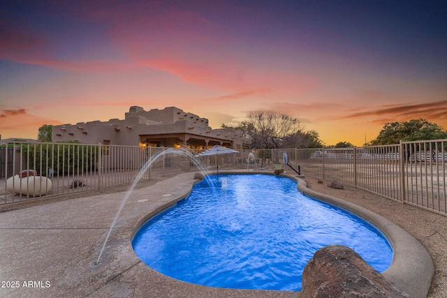 pool at dusk with pool water feature and a patio