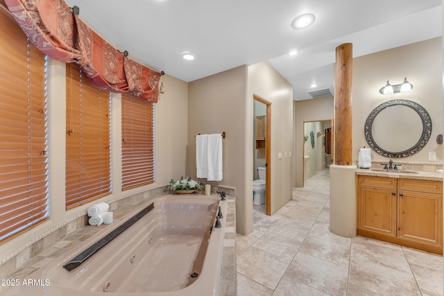 bathroom featuring toilet, vanity, tile patterned floors, and a tub to relax in