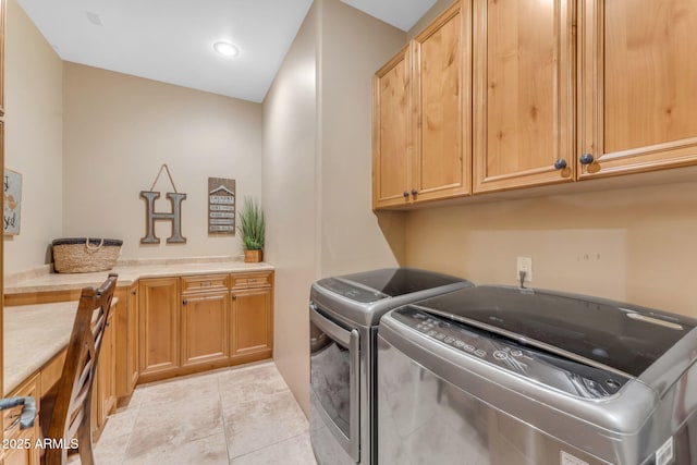 clothes washing area with light tile patterned floors, washing machine and dryer, and cabinets