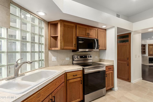 902 W Glendale Ave Unit 102, Phoenix, AZ 85021 - kitchen featuring stainless steel appliances, a sink, brown cabinets, recessed lighting, and backsplash