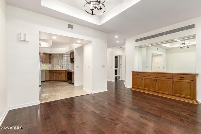 902 W Glendale Ave Unit 102, Phoenix, AZ 85021 - unfurnished living room with a tray ceiling, a chandelier, wood finished floors, recessed lighting, and baseboards