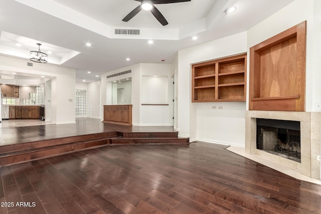 902 W Glendale Ave Unit 102, Phoenix, AZ 85021 - unfurnished living room featuring a raised ceiling, wood finished floors, a tiled fireplace, ceiling fan, and baseboards