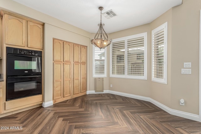 unfurnished dining area featuring dark parquet floors, a healthy amount of sunlight, and a notable chandelier