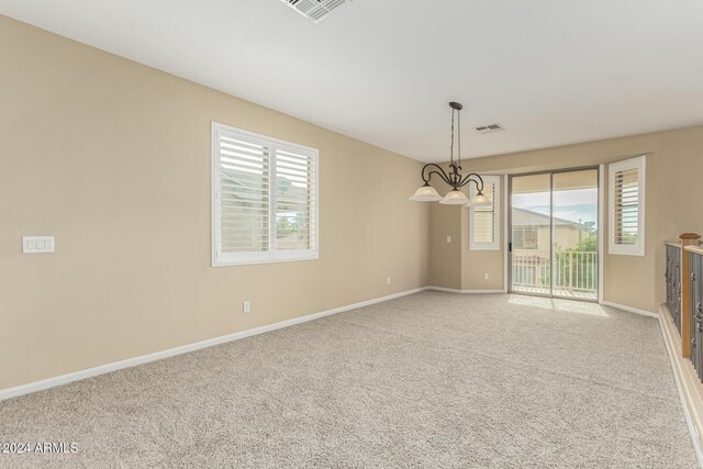 carpeted empty room with a notable chandelier