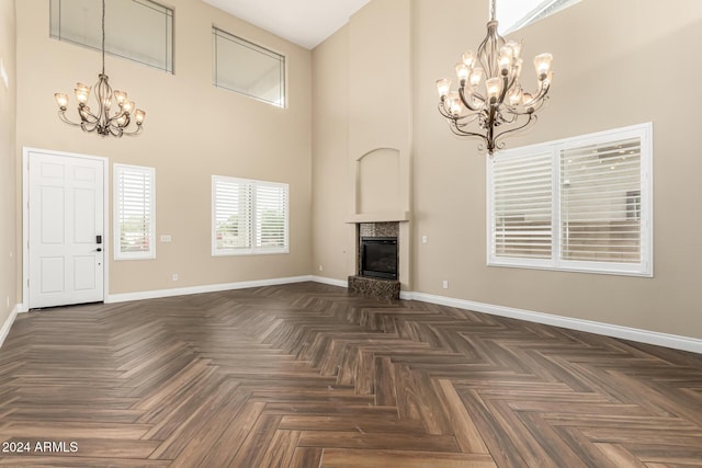 unfurnished living room featuring dark parquet flooring and a towering ceiling