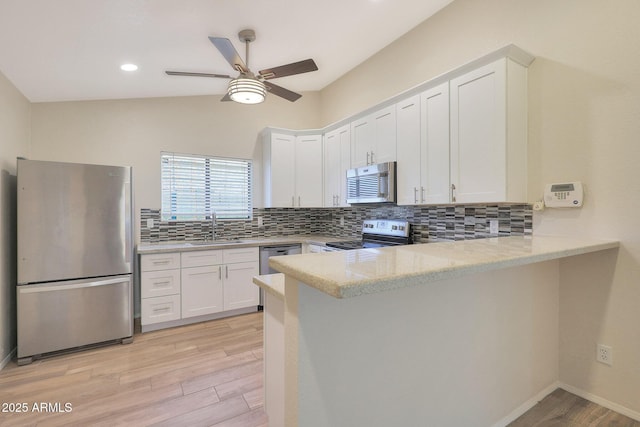 kitchen with sink, white cabinetry, stainless steel appliances, light stone countertops, and kitchen peninsula