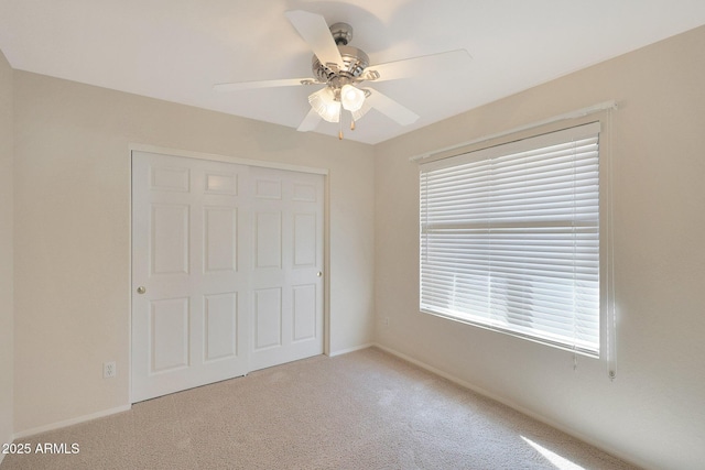 unfurnished bedroom with light carpet, a closet, and ceiling fan