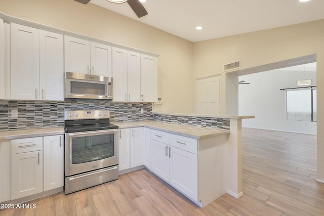 kitchen featuring white cabinetry, backsplash, hanging light fixtures, kitchen peninsula, and stainless steel appliances