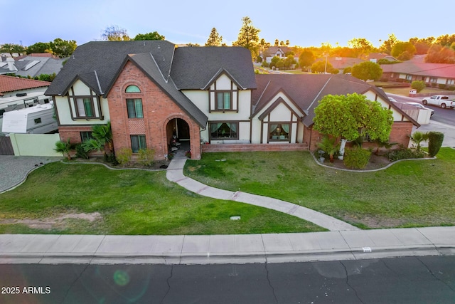 tudor-style house featuring brick siding, stucco siding, and a shingled roof