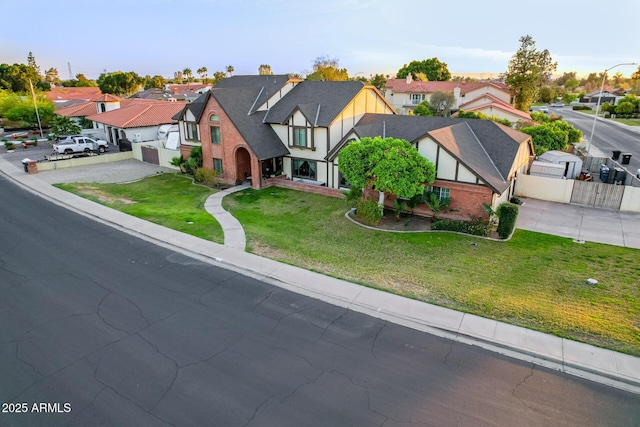 tudor-style house featuring a residential view, concrete driveway, brick siding, and a garage