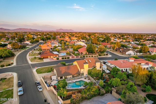 aerial view at dusk of view of pool area, a residential view, and a mountain view