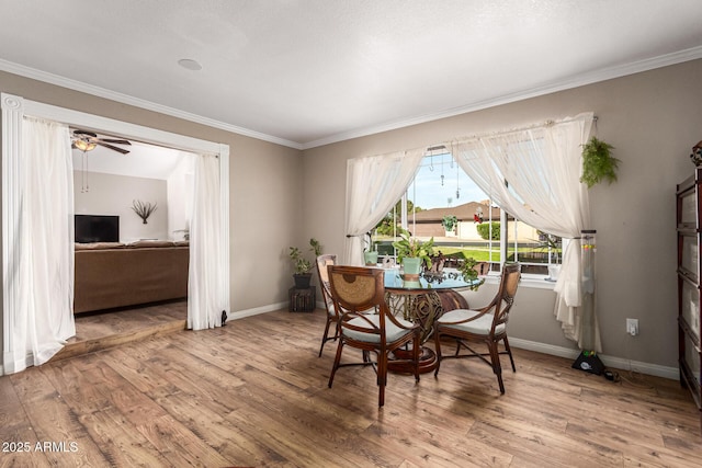 dining space featuring wood finished floors, crown molding, baseboards, and a ceiling fan