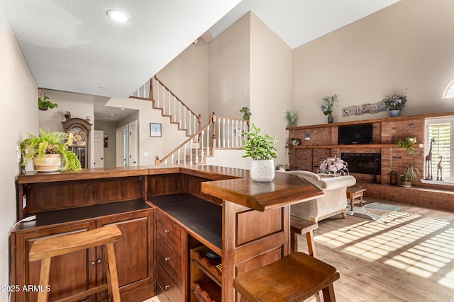 bar featuring high vaulted ceiling, wood finished floors, a fireplace, stairs, and recessed lighting