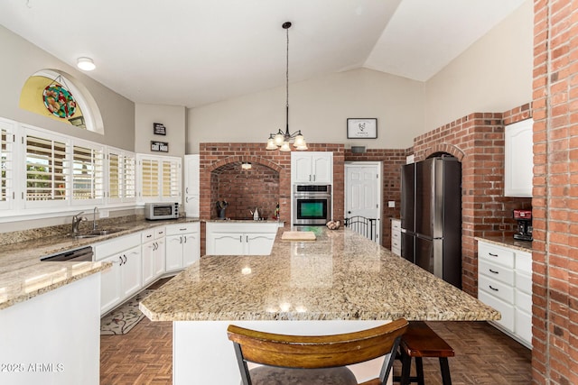 kitchen featuring stainless steel appliances, a sink, white cabinets, a breakfast bar area, and a center island