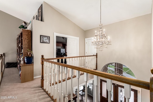 corridor with an upstairs landing, high vaulted ceiling, a chandelier, light colored carpet, and baseboards