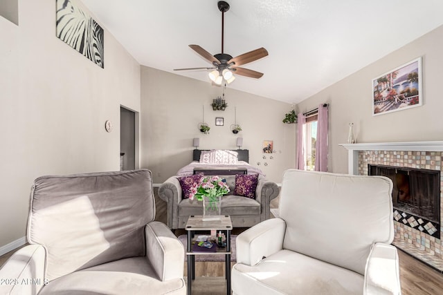 living area with vaulted ceiling, a ceiling fan, wood finished floors, a fireplace, and baseboards