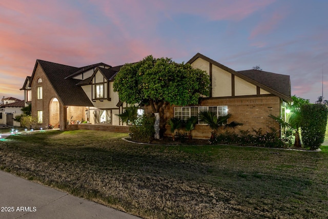 view of front of house featuring brick siding, a front lawn, and stucco siding