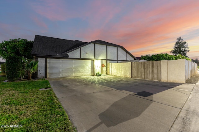 view of front of property with driveway, fence, a gate, an attached garage, and stucco siding