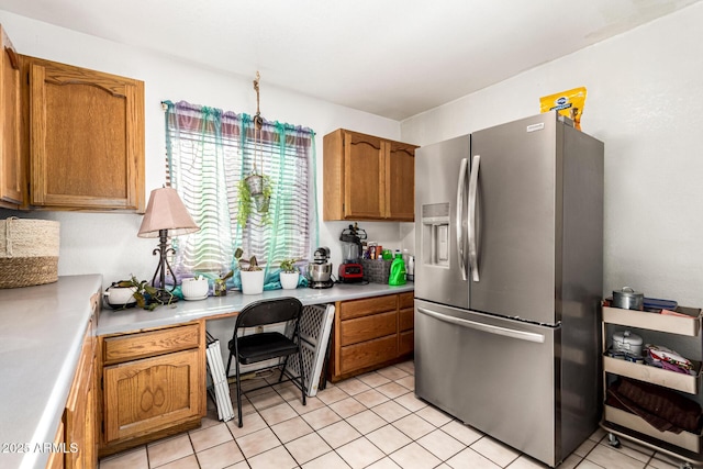 kitchen featuring stainless steel refrigerator with ice dispenser, brown cabinetry, light countertops, and light tile patterned floors