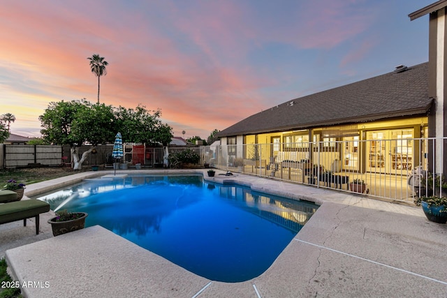 pool at dusk featuring a fenced backyard and a patio area