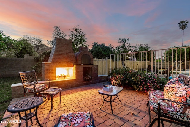 view of patio / terrace with an outdoor brick fireplace and fence