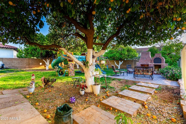 view of yard featuring exterior fireplace, a playground, and a patio